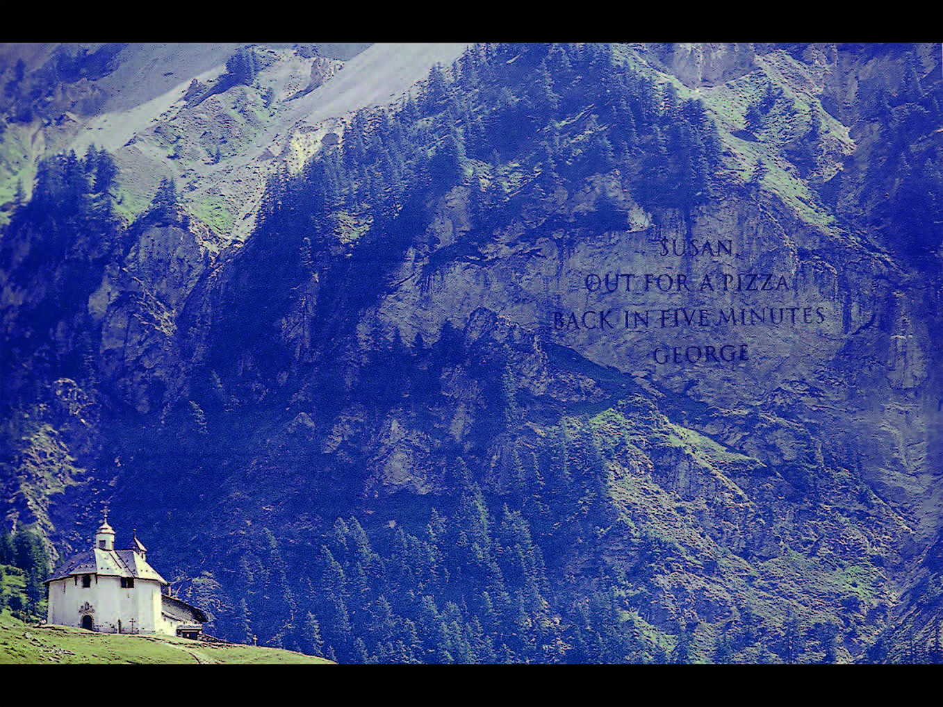A cliffside in the mountains of Switzerland, overlooking an alpine church, the rock face engraved with a phrase, visible for miles around, which reads: ‘Susan. Out for a pizza. Back in five minutes. George.’