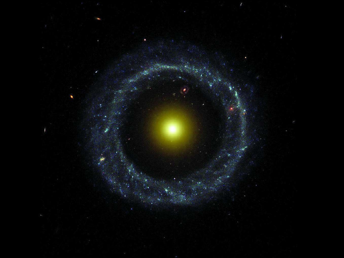 A photograph of Hoag’s Object, a remote galaxy shaped like a perfect annulus of azure stars, encircling a central, radiant sphere of illumination, like a gold core of light inside a ring of dust.